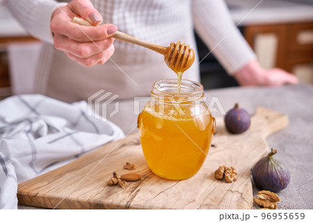 Woman pours honey into a glass jar Woman pours honey into a glass jar 96955659