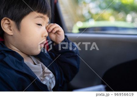 車に乗ってお出かけ中、凄く眠そうに目を擦っている5歳男児 96956619