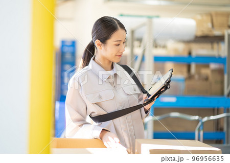 倉庫で検品をする若い女性の作業員 倉庫で検品をする若い女性の作業員 96956635