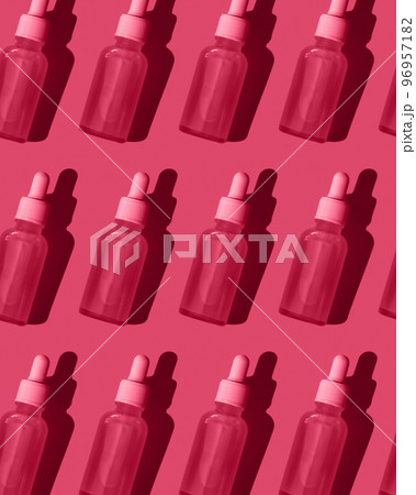 Pattern. Serum in a glass bottle with a dropper on a bright red background. Pattern. Serum in a glass bottle with a dropper on a bright red background. 96957182