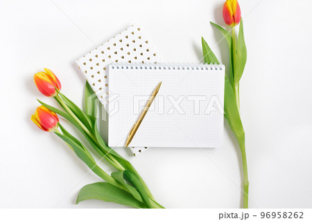 Open spiral notepad with pen and red tulips on white desk background. Template for advertising or visualization of blog with copy space for text. Business holiday Valentine card. Spring and Birthday. 96958262