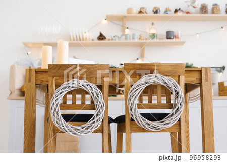 Wooden kitchen chairs decorated with Christmas wreaths in Scandinavian cuisine 96958293