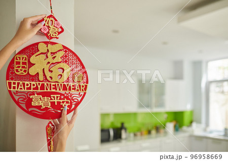 Hands of woman hanging round pedant on wall to decorate house for Lunar festival Hands of woman hanging round pedant on wall to decorate house for Lunar festival 96958669