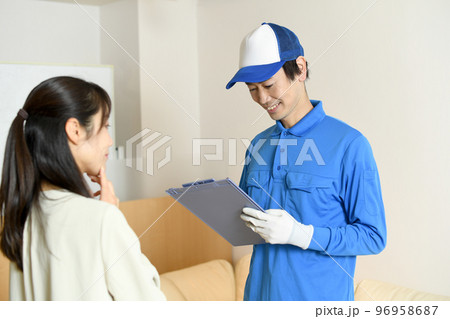 会話をする作業員の男性と若い女性 96958687
