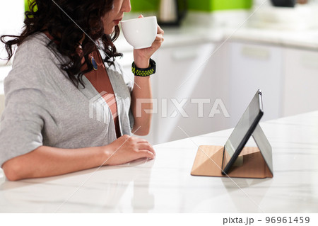 Woman drinking morning coffee and watching news of entertaining video on tablet 96961459
