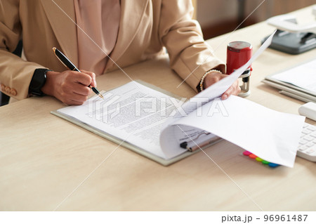 Female entrepreneur signing contract on office desk Female entrepreneur signing contract on office desk 96961487