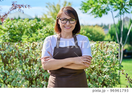 Outdoor portrait smiling female gardener looking at camera in backyard Outdoor portrait smiling female gardener looking at camera in backyard 96961793