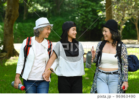 Happy senior women friends and asian girl talking to each other and walking in the park with in a spring time 96963490