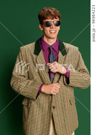Studio footage young man in vintage fashion style costume, suit posing isolated on dark green background. Concept of retro style, creativity, emotions, facial expression, fashion 96964223