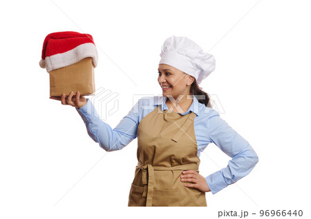 Isolated portrait on white background, multi-ethnic waitress bartender, baker confectioner in chef's apron, holding takeaway food and drink packed in a paper bag with Santa hat. Delivery at Christmas 96966440
