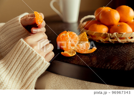 冬、こたつの上でみかんを食べる女性 96967343