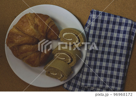 Croissants, jam rolls on a white plate, served with coffee Croissants, jam rolls on a white plate, served with coffee 96968172