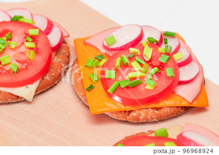 Crispy Cracker Sandwiches with Tomato, Sausage, Cheese, Green Onions and Radish 96968924