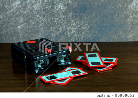 Old Stereo Slide Viewer and Glass Slides on a Polished Wooden Surface Old Stereo Slide Viewer and Glass Slides on a Polished Wooden Surface 96969653