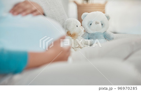 Mother, stomach and teddy bear in the background while relaxing on the sofa at home. Pregnancy, maternity and female rest in her house with toys while preparing for parenthood and motherhood 96970285