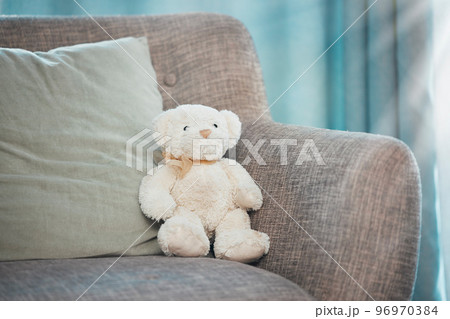 Lonely, loss and adoption with a teddy bear abandoned on a sofa in an empty living room of a home. Lost, alone and grief with a stuffed animal sitting on a couch in the lounge of a house alone 96970384