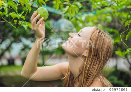 Young woman smelling the passion fruit in the garden 96972861