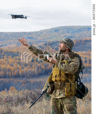 Vertical photo of an artillery spotter or military observer launch a drone into the sky for reconnaissance in enemy territory. Vertical photo of an artillery spotter or military observer launch a drone into the sky for reconnaissance in enemy territory. 96973980