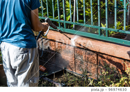 Worker using high pressure water jet spray gun to wash and clean away dirty wall with moss in renovation Worker using high pressure water jet spray gun to wash and clean away dirty wall with moss in renovation 96974630