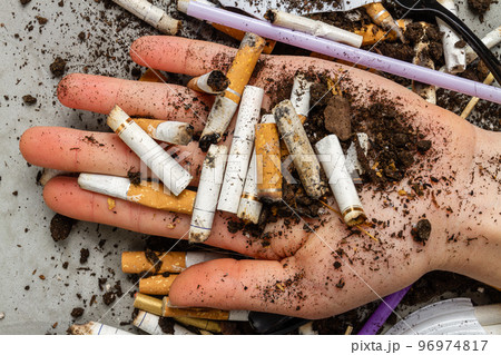 Close up hand holding pile of cigarettes with dirt. Concept of enviroment pollution. Close up hand holding pile of cigarettes with dirt. Concept of enviroment pollution. 96974817