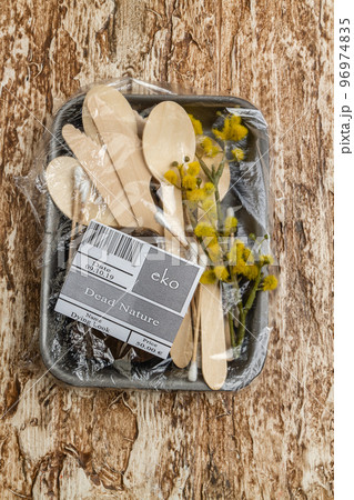 Wooden utensils with spoon and herb wrapped in plastic. Dead nature concept. Vertical shot top view. 96974835