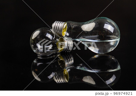 Two turned off light bulbs on black background with reflection. Two turned off light bulbs on black background with reflection. 96974921