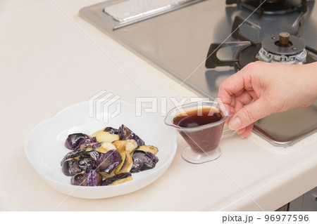 【茄子の揚げびたしを作る　炒めた茄子に麵つゆを入れる】 96977596