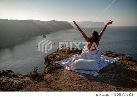 Woman wake up in bed wuth duvet and pillow over nature sea background outdoors. Back view. Good morning. Freedom concept. 96977633