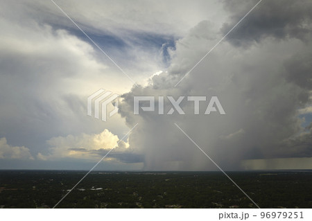 Dark stormy clouds forming on gloomy sky during heavy rainfall season over suburban town area Dark stormy clouds forming on gloomy sky during heavy rainfall season over suburban town area 96979251