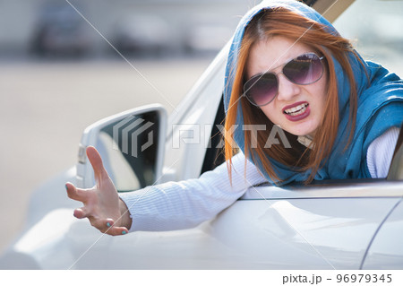 Closeup portrait of pissed off displeased angry aggressive woman driving a car shouting at someone with hand fist up. Negative human expression consept. 96979345