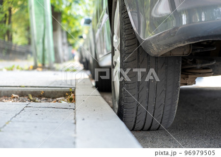 Closeup of a car wheel parked near curb on the side of the street on a parking lot. 96979505