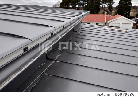 Close-up detail of house roof made from gray metal sheets. 96979636