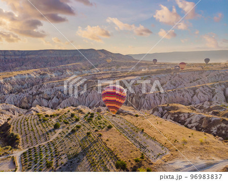 Colorful hot air balloons flying over at fairy chimneys valley in Nevsehir, Goreme, Cappadocia Turkey. Spectacular panoramic drone view of the underground city and ballooning tourism. High quality Colorful hot air balloons flying over at fairy chimneys valley in Nevsehir, Goreme, Cappadocia Turkey. Spectacular panoramic drone view of the underground city and ballooning tourism. High quality 96983837