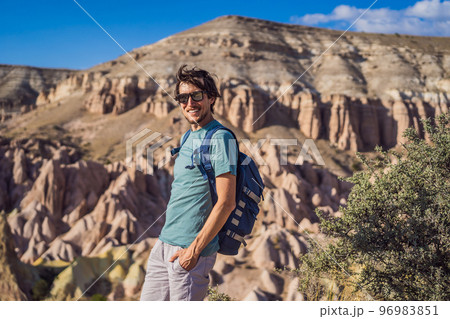 Young man exploring valley with rock formations and fairy caves near Goreme in Cappadocia Turkey Young man exploring valley with rock formations and fairy caves near Goreme in Cappadocia Turkey 96983851