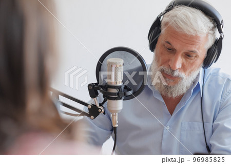 older man with gray hair and female guest in a recording studio are recording podcast older man with gray hair and female guest in a recording studio are recording podcast 96985825