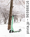 Green rental scooter standing near beautiful tree covered with snow 96986616