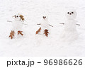 Cute three white snowmen standing at the snowy ground background 96986626