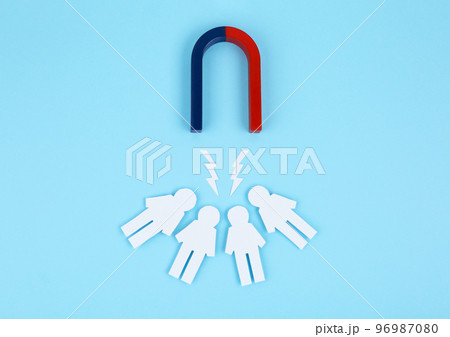 Magnet attracting paper people on light blue background, flat lay 96987080