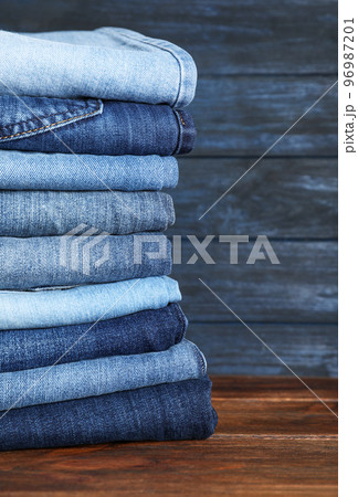 Stack of different jeans on wooden table. Space for text 96987201