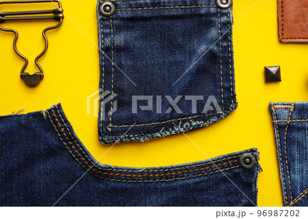 Flat lay composition with garment accessories and cutting details for jeans on yellow background Flat lay composition with garment accessories and cutting details for jeans on yellow background 96987202