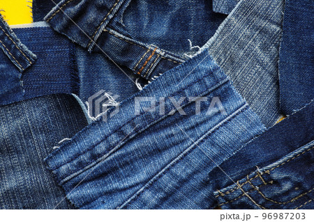 Many patches of old jeans on yellow background, top view Many patches of old jeans on yellow background, top view 96987203