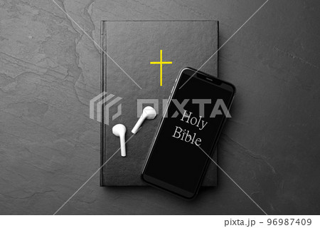 Bible, phone and earphones on black background, top view. Religious audiobook Bible, phone and earphones on black background, top view. Religious audiobook 96987409