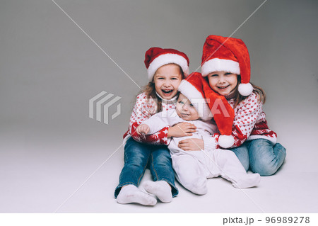 Laughing sisters with baby brother at xmas. Laughing sisters with baby brother at xmas. 96989278