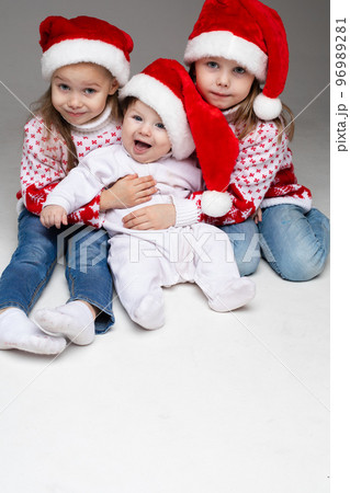 Laughing sisters with baby brother at xmas. Laughing sisters with baby brother at xmas. 96989281