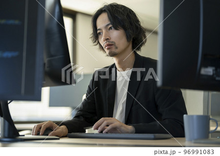 デスクトップパソコンで作業をする30代前半の男性 96991083
