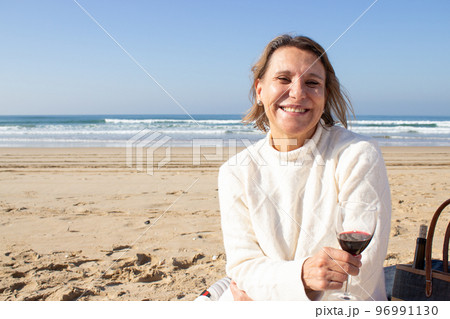 Happy senior woman drinking wine at seashore Happy senior woman drinking wine at seashore 96991130