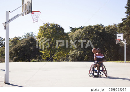 Bearded man in sports wheelchair playing basketball 96991345