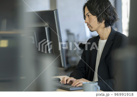 デスクトップパソコンで作業をする男性の横顔 デスクトップパソコンで作業をする男性の横顔 96991918