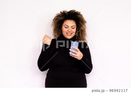 Satisfied young woman looking at smartphone screen Satisfied young woman looking at smartphone screen 96992117