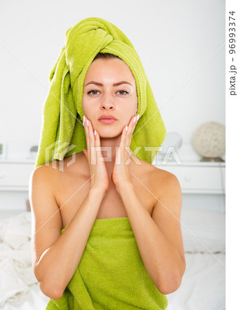 Girl in towel doing facial massage 96993374